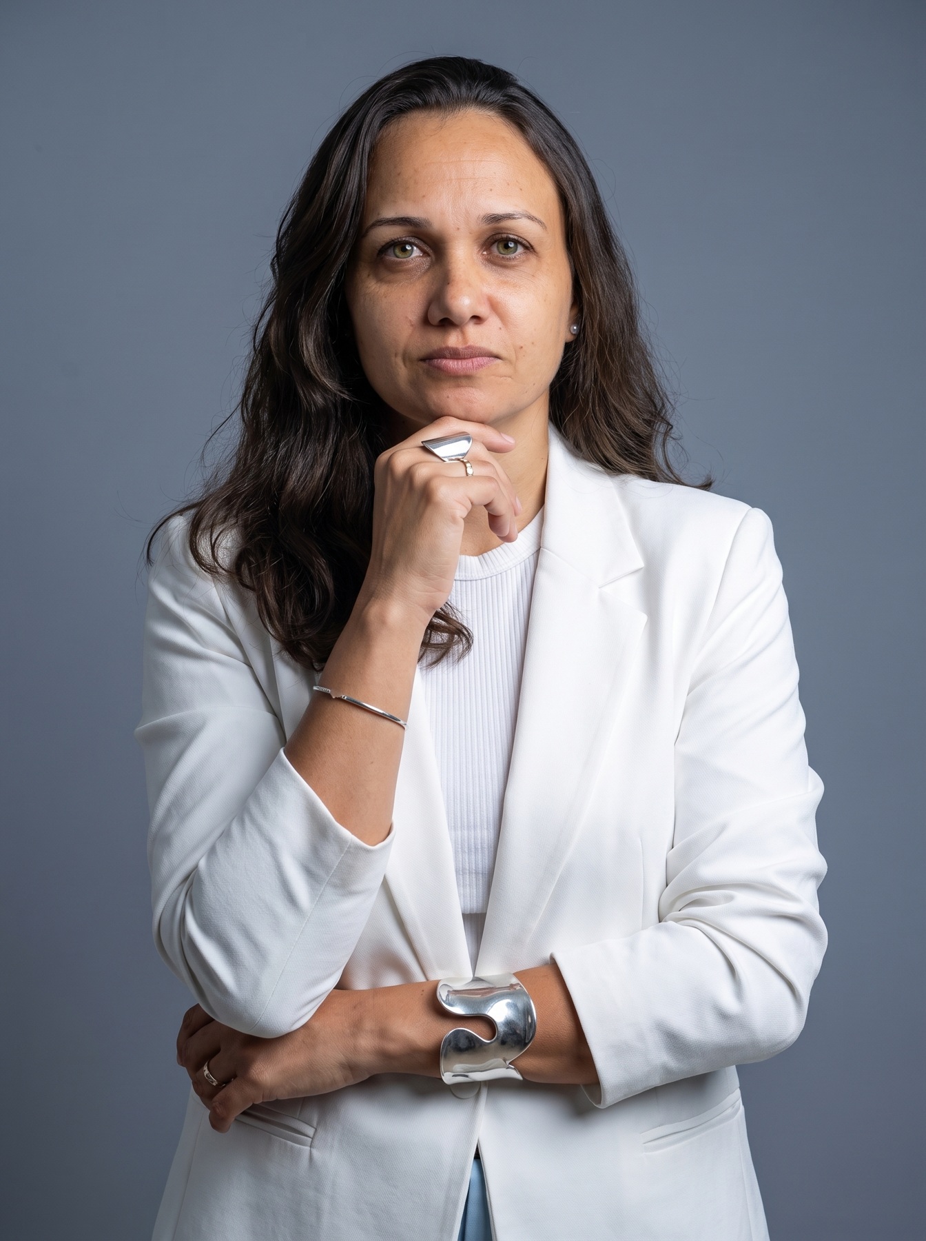 Juliana Guedes com roupa branca e a mão no queixo